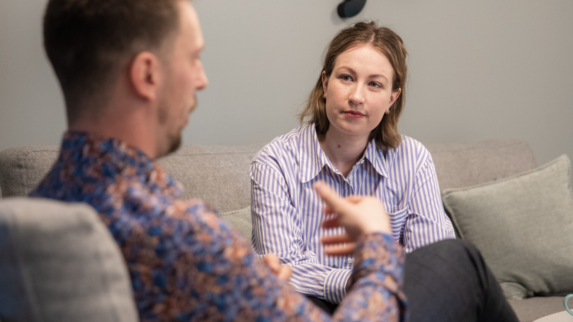 Två personer samtalar. De sitter i en varsin fåtölj snett vridna mot varandra, vilket är bra när man ska ge negativ feedback.