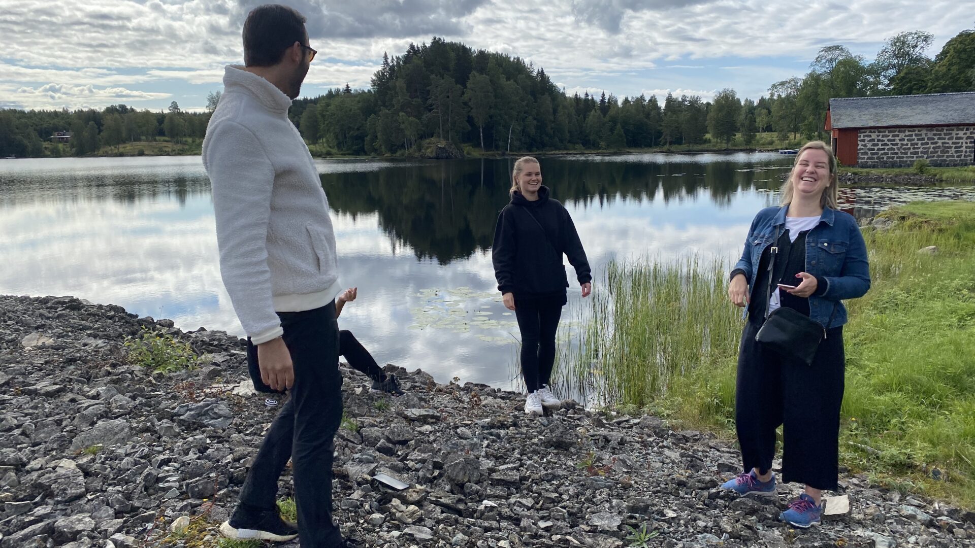Tre personer som skrattar, i bakgrunden en stilla sjö.
