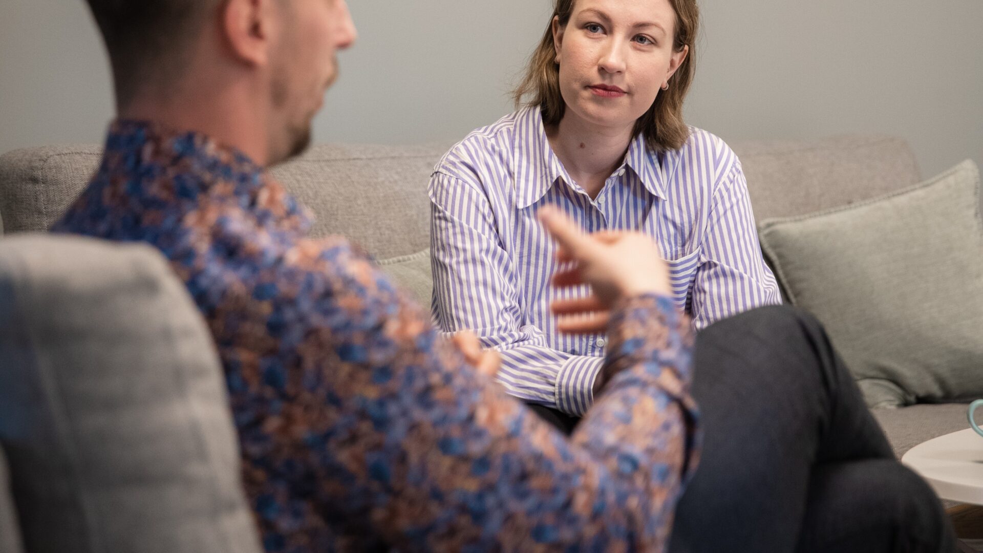 Två personer samtalar. De sitter i en varsin fåtölj snett vridna mot varandra, vilket är bra när man ska ge negativ feedback.