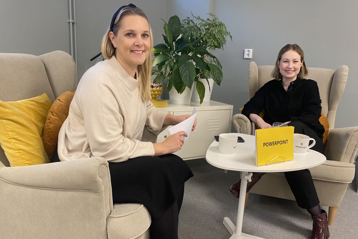 Två personer, som båda tittar in i kameran, sitter i varsin fåtölj. En skylt på bordet visar att de pratar om PowerPoint.